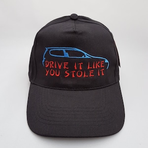May include: Black baseball cap with a blue car silhouette and the text "Drive it like you stole it" embroidered in red.