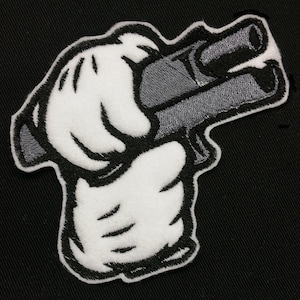 May include: A white cartoon hand holding a grey gun with the barrel pointing to the right.