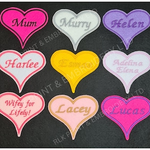 May include: Nine felt heart-shaped patches with embroidered names. The names are: Mum, Murry, Helen, Harlee, Esmae, Adelina Elena, Wifey for Lifely!, Lacey, and Lucas. The hearts are in various colours, including pink, white, purple, yellow, and light pink.