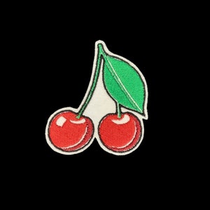 May include: A red and green embroidered patch of two cherries with a stem and leaf.
