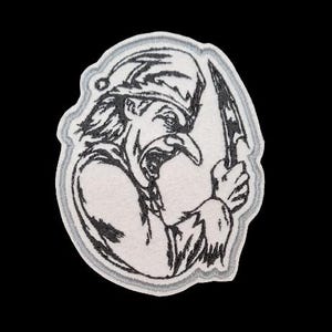 May include: A white embroidered patch featuring a black and white illustration of a jester holding a knife.