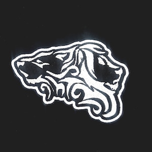 May include: White embroidered design of a stylised wolf head on a black background.