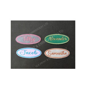 May include: Four embroidered name patches in an oval shape. The names Tilly, Alexander, Jacob, and Samantha are embroidered in different colours on a grey, green, light blue, and tan background, respectively. The patches are on a dark grey surface.