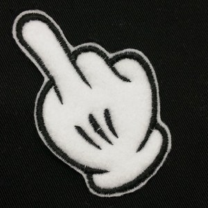 May include: A white felt hand with black stitching giving the middle finger. The hand is on a black background.