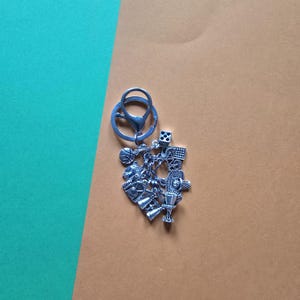 May include: Silver keychain with a basketball, trophy, whistle, and other sports-themed charms.