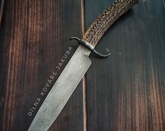 May include: A large,  handmade knife with a  brown antler handle and a  steel blade. The blade is etched with the text "DÍLNA KOVAŘE JAKUBA".
