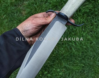 May include: A large, handmade knife with a light-colored antler handle and a wide, polished steel blade. The blade has a dark, unpolished section near the handle. The text "DÍLNA KOV JAKUBA" is visible.
