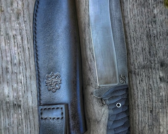 May include: A black leather sheath with a stitched design and a black knife with a textured black handle and a silver blade. The knife has a small silver logo on the blade.