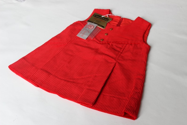 May include: A red sleeveless corduroy dress with a small tag that says "Craftsman" and "Little Girl".