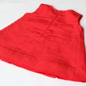 May include: A red corduroy sleeveless dress with a zipper in the back.