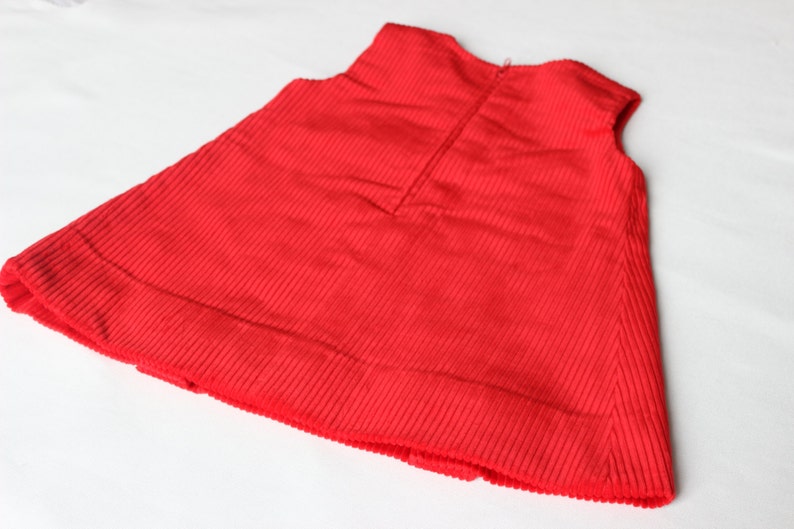 May include: A red corduroy sleeveless dress with a zipper in the back.