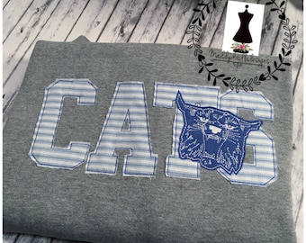 May include: Gray sweatshirt with the word "CATS" in blue and white striped fabric. The "S" is replaced with a blue and white striped image of a wildcat.