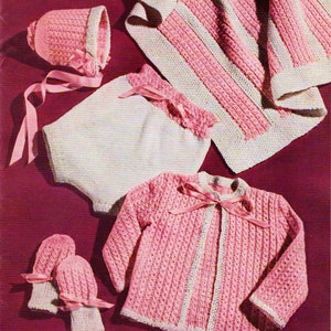 May include: A set of knitted baby clothes in pink and white, including a cardigan, a bonnet, a soaker, and mittens. The text "INFANT SIZES" is visible in the image.