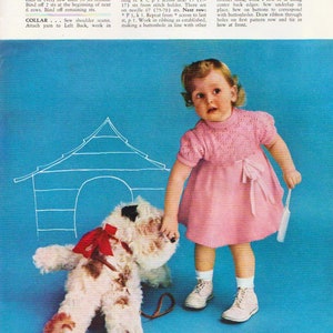 May include: A young girl in a pink knitted dress with a white collar and a bow at the waist, stands in front of a blue background. She is holding a white brush and looking at a white stuffed dog with a red bow. The text "TODDLER SIZES -13- " is at the bottom of the image.