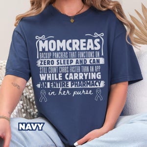 May include: Navy blue t-shirt with white text that reads "MOMCREAS BACKUP PANCREAS THAT FUNCTIONS ON ZERO SLEEP AND CAN STILL COUNT CARBS FASTER THAN AN APP WHILE CARRYING AN ENTIRE PHARMACY in her purse". The word "NAVY" is at the bottom.