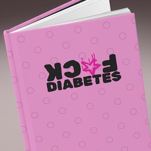 May include: Pink notebook with white pages and a pink cover featuring a pattern of light pink circles. The cover has the words "F*CK DIABETES" in black and pink lettering.