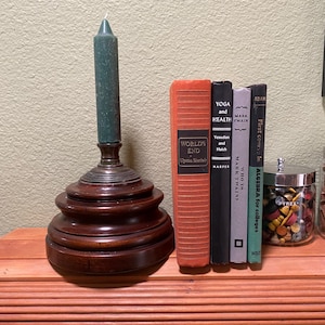 May include: A wooden candle holder with three tiers, a teal candle, and a stack of books. The books are titled "Worlds End", "Yoga and Health", "Who Is Mark Twain?", and "Algebra for Colleges".