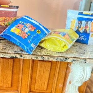 May include: Four bags of different flavored potato chips on a brown countertop. The bags are blue, yellow, red, and white. The blue bag says "Classic Mix 18 oz" and the white bag says "Simply".