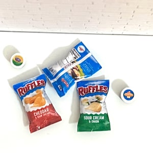 May include: Two bags of Ruffles potato chips, one with cheddar and sour cream flavor and the other with sour cream and onion flavor. There are two small containers of dip.