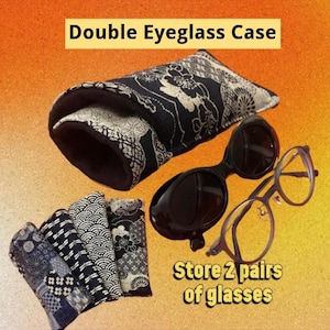 May include: A double eyeglass case with a black and white floral pattern, accompanied by a pair of dark sunglasses and a pair of clear-lens glasses. The text reads Double Eyeglass Case and Store 2 pairs of glasses. The case has a soft interior.