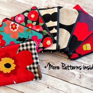 May include: A collection of colorful zippered pouches with various floral and geometric patterns. The pouches are arranged in a semi-circle on a wooden surface. The text '+More Patterns inside' is visible at the bottom of the image.
