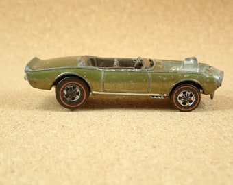 May include: A green toy car with black wheels and a detailed engine. The car is a vintage Hot Wheels model.