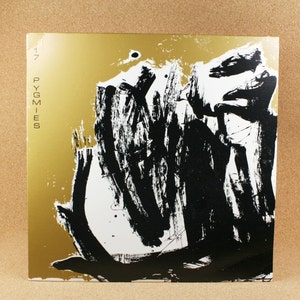 May include: A gold record with black and white abstract art. The record is titled "Pygmies" and has the number "17" printed on the left side.