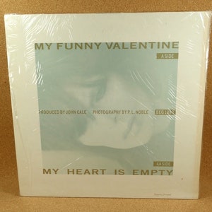 Puede incluir: Una portada de disco de vinilo blanco con una foto en azul y blanco de la cara de una mujer. El texto en la portada dice "My Funny Valentine" y "My Heart Is Empty".