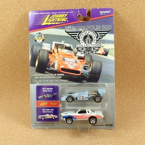 Peut inclure: Un ensemble de voitures miniatures Johnny Lightning Indianapolis 500 Champions Collection comprenant une voiture de Bobby Unser, vainqueur de 1975, et une voiture de course Buick Century de 1975. Les voitures sont dans une vitrine en plastique avec un fond bleu et blanc.