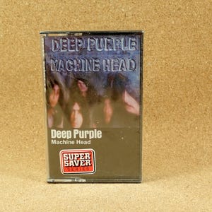 May include: A cassette tape with a black and white photo of the band Deep Purple on the front. The title "Deep Purple Machine Head" is printed in white on a black background. The cassette tape is labeled "Super Saver Series".