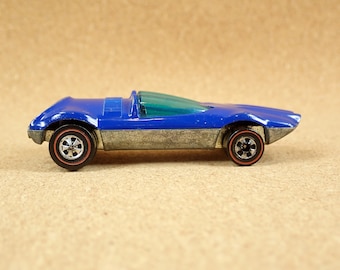 May include: A blue and silver toy car with a clear windshield. The car has red wheels and a detailed design.