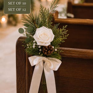 Puede incluir: Un arreglo floral con una rosa blanca, agujas de pino verdes, ramas de cedro, hojas de eucalipto, paniculata y una piña marrón, atado con una cinta de satén color crema. El texto en la imagen dice: SET OF 6, SET OF 10, SET OF 12.