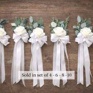 Op de afbeelding: Vijf bloemboeketten met witte rozen, witte strikken en lange witte linten. De boeketten zijn versierd met groen en kleine blauwe bloemen. De tekst op de afbeelding luidt "Sold in set of 4 - 6 - 8 - 10".