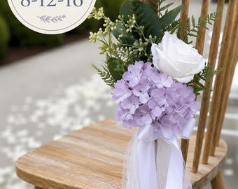 Könnte beinhalten: Ein Holzstuhl, geschmückt mit einem Blumenarrangement aus einer weißen Rose, hellvioletten Hortensienblüten und grünem Blattwerk. Ein weißes Satinband und Tüllstoff hängen herab. Der Text auf dem Bild lautet: SOLD IN SETS OF 8-12-16.