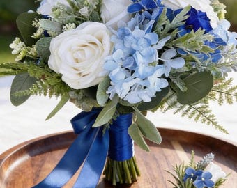 Könnte beinhalten: Ein Brautstrauß mit weißen Rosen, hellblauen Hortensien und grünen Akzenten. Der Strauß ist mit einem königsblauen Satinband gebunden. Ein passendes Knopfloch mit ähnlichen Blumen und Band ist ebenfalls vorhanden.