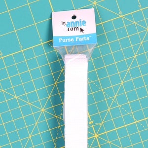 May include: White cotton webbing strap packaged in a clear plastic bag with a label that reads "by annie.com Purse Parts".