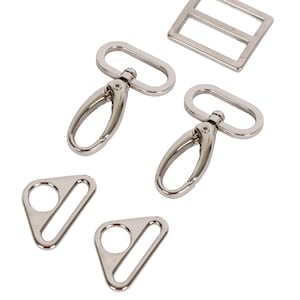 May include: Set of silver metal hardware for bags and purses. Includes two swivel clasps, two triangular D-rings, and one rectangular buckle.