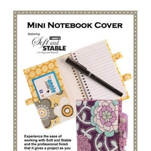 May include: A sewing pattern for a mini notebook cover featuring a floral design and a pen holder. The pattern is by Annie and includes instructions for making a quick and easy notebook cover.