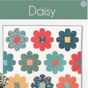 May include: A Daisy quilt with large, colorful flower patterns in shades of red, blue, green, and yellow on a white background. The quilt is displayed on a wall. The text "Daisy" and "A fat quarter quilt in 5 sizes" are visible.