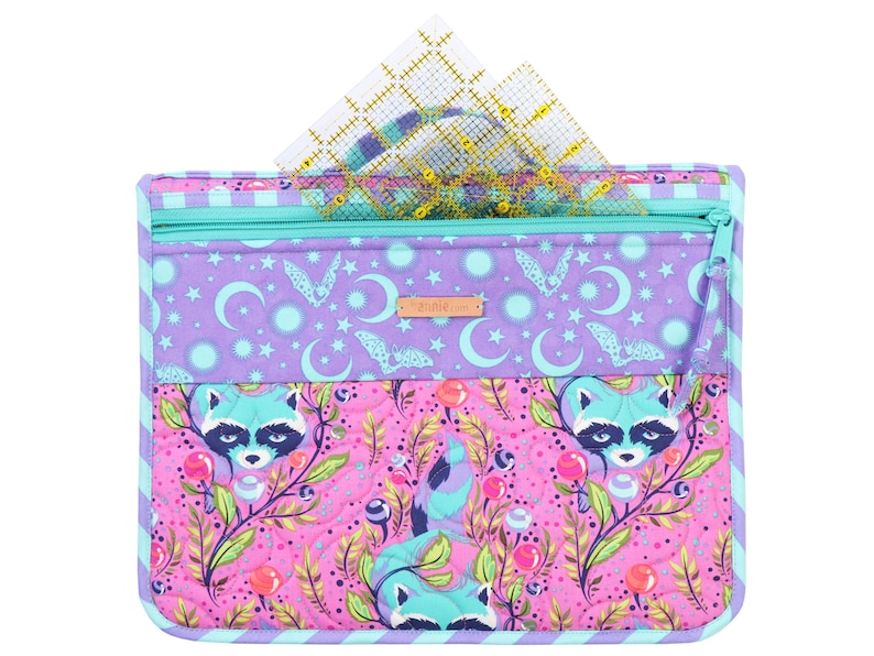 May include: A purple and pink quilted zippered pouch with a raccoon print and a zippered pocket on the top. The pouch has a teal zipper and a blue and white striped border. The pouch is filled with clear plastic rulers.