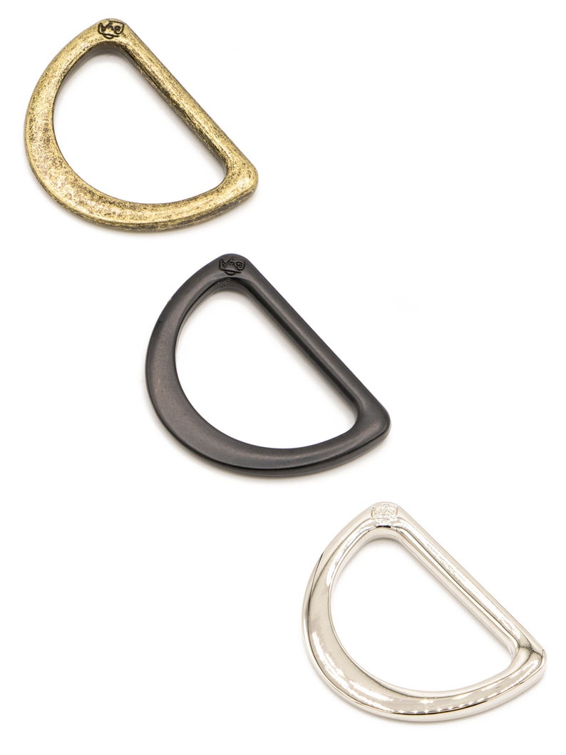 Puede incluir: Tres anillas en D en diferentes acabados: lat&oacute;n antiguo, negro y n&iacute;quel. Cada anillo tiene un peque&ntilde;o logotipo estampado en la parte superior.