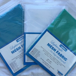 May include: Three packages of lightweight mesh fabric in white, teal, and green. The packages are labeled "Lightweight Mesh Fabric" and include instructions for use and care. The fabric is 18 inches by 54 inches and is 100% polyester.