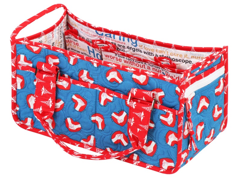 May include: A blue and red quilted tote bag with a zipped pocket and multiple pockets on the front. The bag has a red handle and is decorated with a white print of a heart with a caduceus symbol. The bag is lined with a white fabric with text that reads "Nurses are angels with a stethoscope. If love can't cure it, nurses can't cure it. We'd be worse without a nurse."
