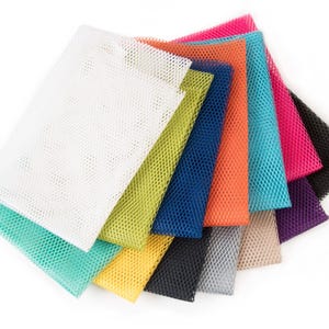 May include: A collection of colorful mesh fabric swatches in various shades, including white, green, blue, orange, pink, and black. The swatches are arranged in a fan shape, showcasing the different colors and textures of the material.