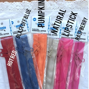 May include: Assortment of 30-inch double slide handbag zippers in various colors, including hot red, blast off blue, pumpkin, natural, lipstick, and raspberry.