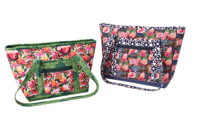 Puede incluir: Dos bolsos de mano de tela con estampado floral y ribetes verdes y azules. El bolso de la izquierda tiene un ribete verde y el bolso de la derecha tiene un ribete azul.