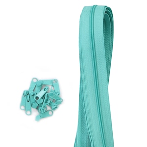 May include: A close-up of a teal zipper with multiple zipper pulls. The zipper is folded in half and the zipper pulls are scattered around it.