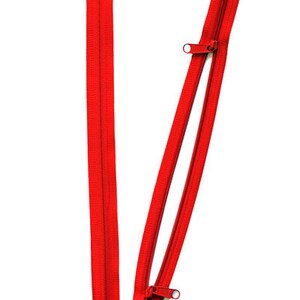 May include: A red zipper with two sliders. The zipper is open and the sliders are at the top of the zipper.