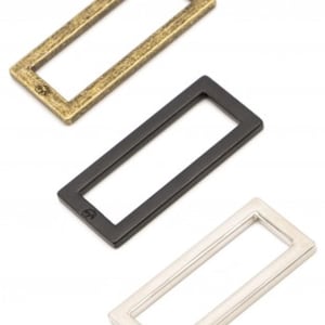 May include: Three metal rectangular frames in gold, black, and silver. The frames are about 2 inches long and 1 inch wide.