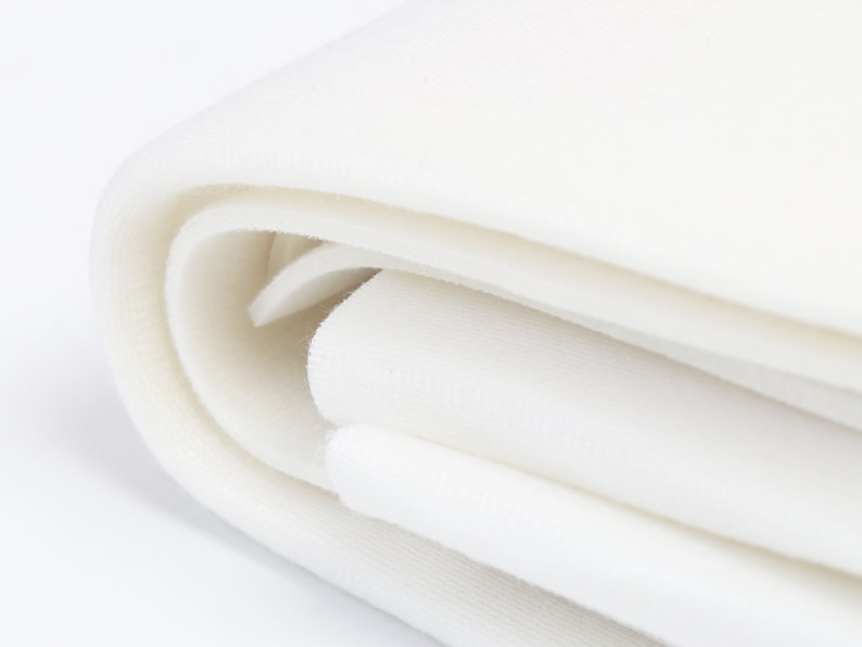 May include: A close-up of a white fabric backdrop folded in half. The fabric is smooth and appears to be made of a soft material.